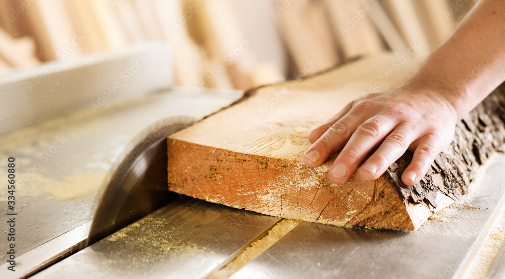 Worker hands details of wood cutter machine with a circular saw and wooden board. Circular cutting saw in action. Worker hands details of wood cutter machine with a circular saw and wooden board. Circular cutting saw in action.