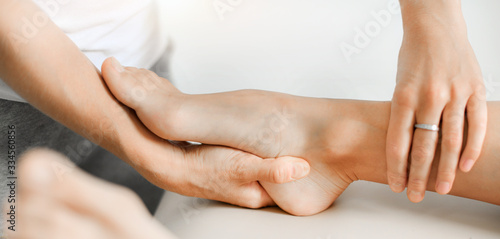 Professional therapist giving relaxing leg massage treatment to athlete woman in therapy centre.