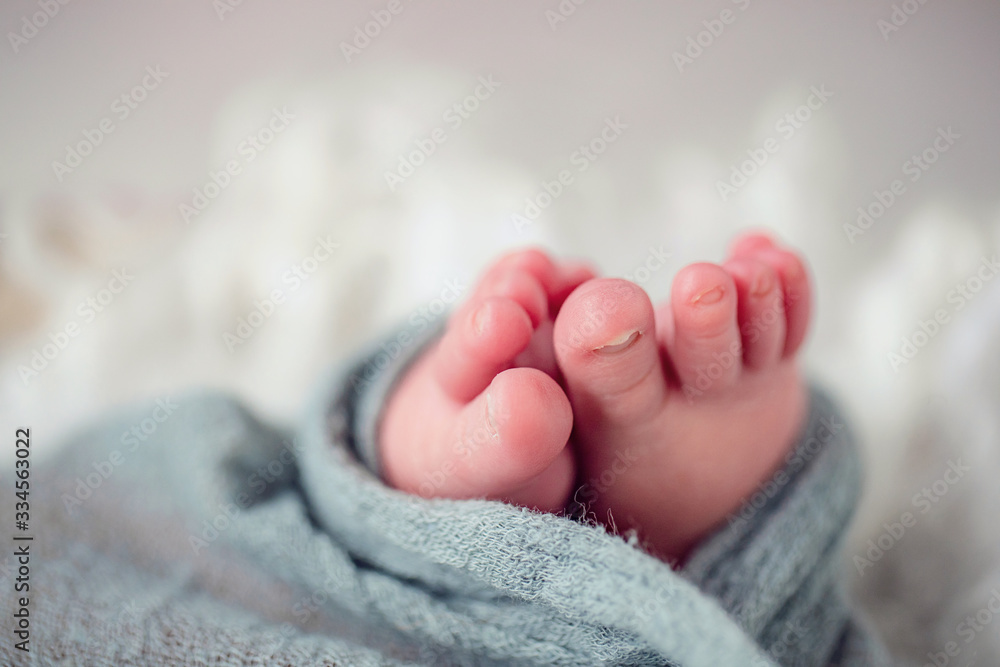 Newborn Baby Toes in blue swaddle on neutral background Newborn Baby Toes in blue swaddle on neutral background