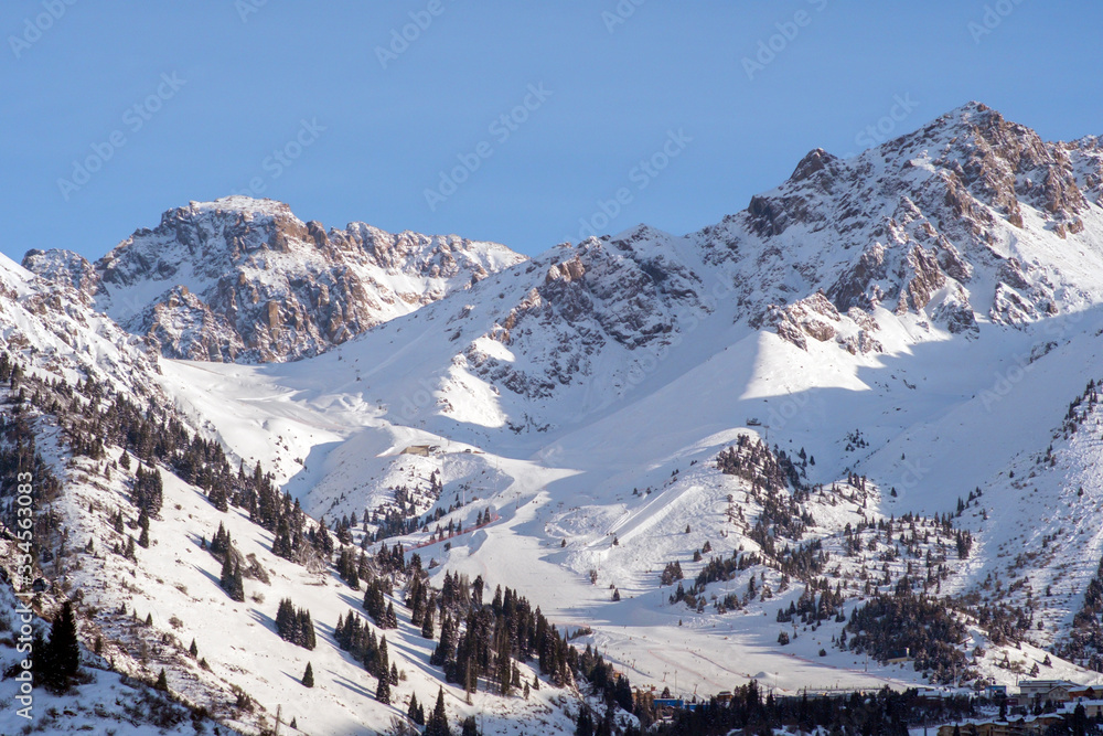Shymbulak gorge and mountains with ski slopes. Winter mountains landscape. Nature, travel, adventure, hiking.