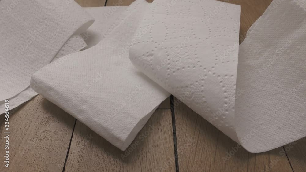 Camera panning over unrolled white toilet paper lying on wooden floor. Camera panning over unrolled white toilet paper lying on wooden floor.