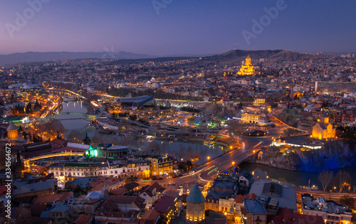 Fototapeta Naklejka Na Ścianę i Meble -  Panoramic view of Tbilisi city from NArikala fortress after the sunset during blue hour. Light trails of traffic and romantic Georgia concept. 2020