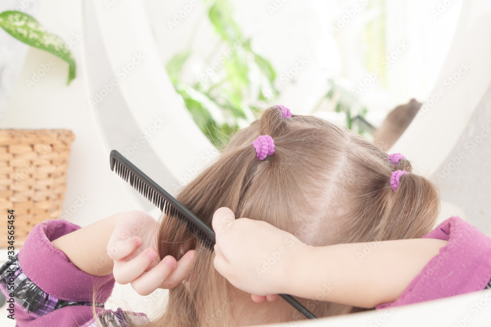 Naklejka premium girl in a purple dress combing herself in front of a mirror