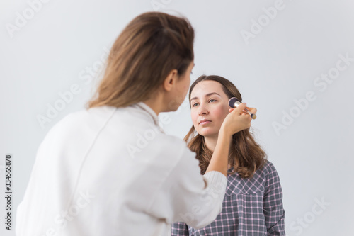 Beauty and cosmetics concept - Makeup artist doing professional make up of young woman