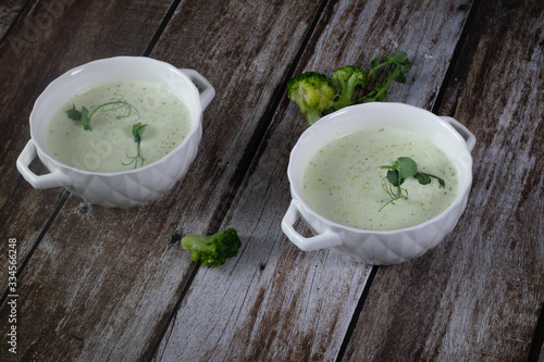 fresh broccoli cream soup with micro greens on dark wooden background