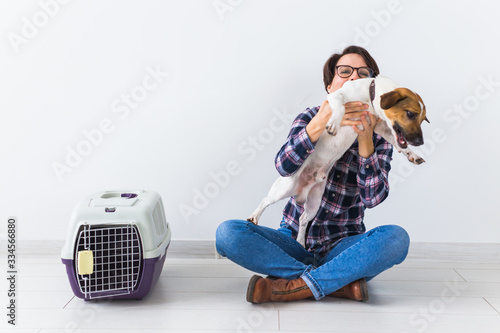 Dog carrying bags and pets owner concept - Attractive cheerful female in plaid shirt holds favourite pet. Happy woman with her jack russell terrier