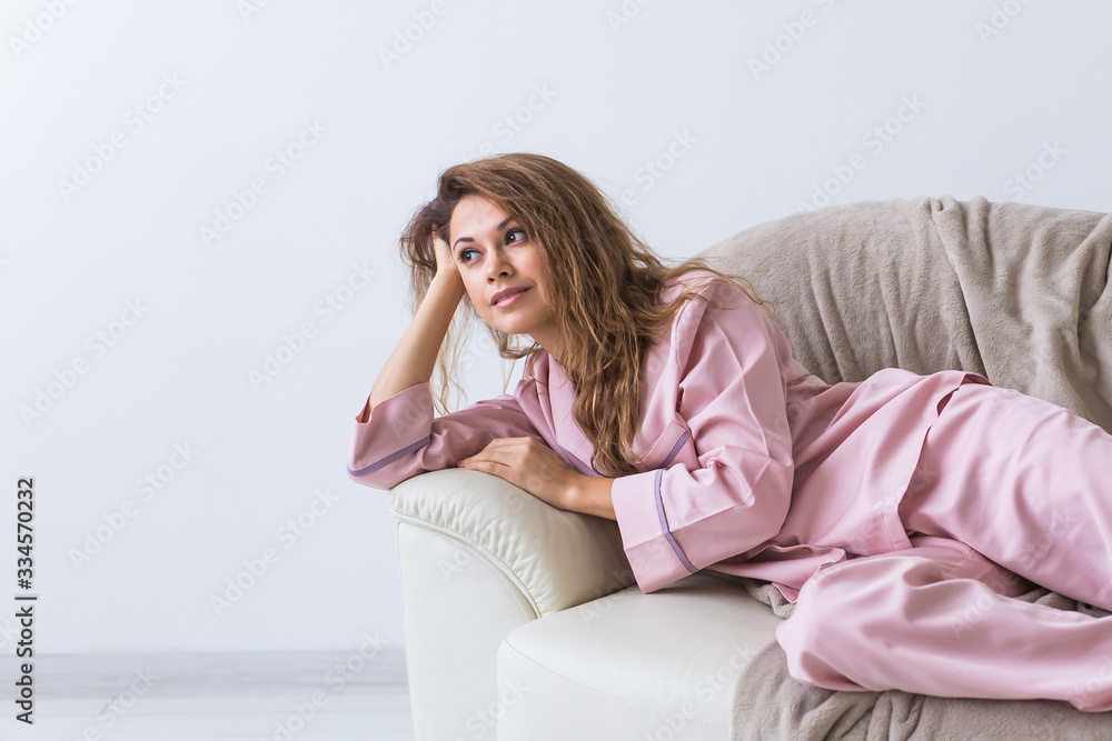 Young attractive woman dressed in beautiful colorful pajama posing as a model in her living room. Comfortable sleepwear, home relaxation and female fashion concept. Young attractive woman dressed in beautiful colorful pajama posing as a model in her living room. Comfortable sleepwear, home relaxation and female fashion concept.