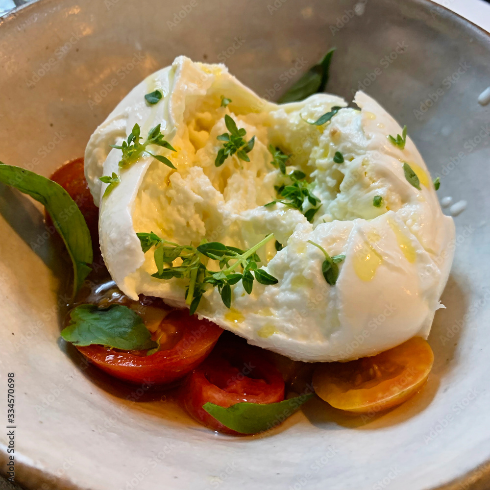 Fresh buffalo mozzarella on tomatoes with basil, thyme and olive oil 