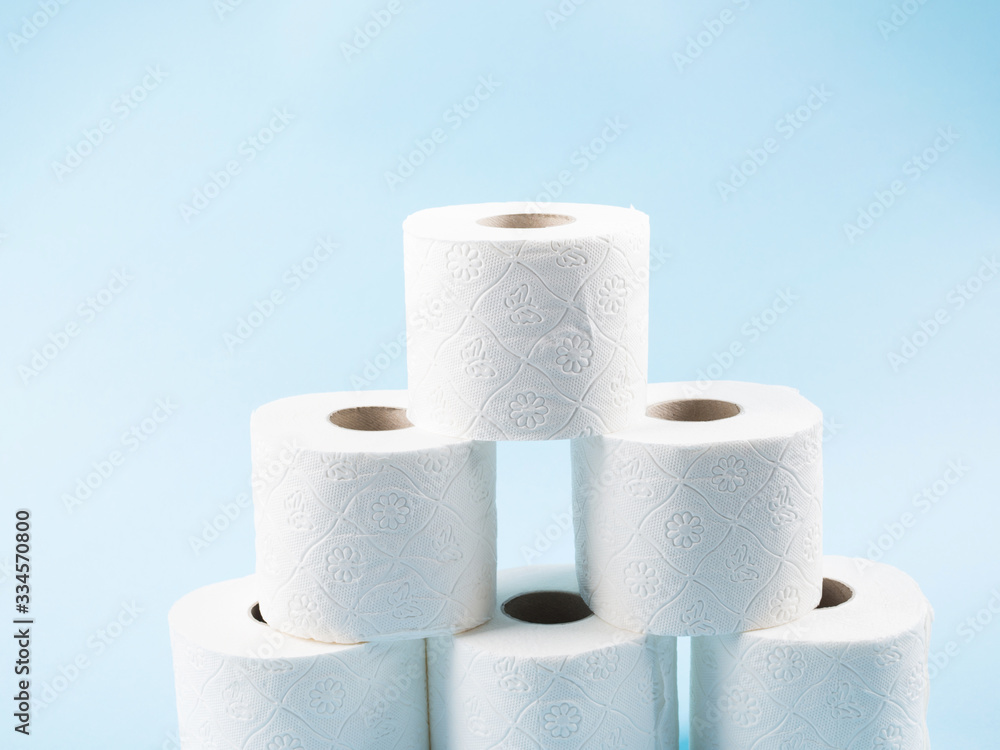 Stack of white toilet paper rolls on blue abstract background. Personal hygiene supplies for restroom. Panic concept during coronavirus pandemic. Stack of white toilet paper rolls on blue abstract background. Personal hygiene supplies for restroom. Panic concept during coronavirus pandemic.