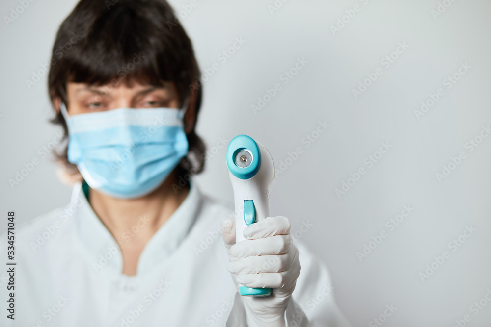 Doctor wearing protective mask ready to use infrared forehead thermometer to check body temperature for virus symptoms - epidemic virus outbreak concept. Coronavirus.Thermometer gun Doctor wearing protective mask ready to use infrared forehead thermometer to check body temperature for virus symptoms - epidemic virus outbreak concept. Coronavirus.Thermometer gun