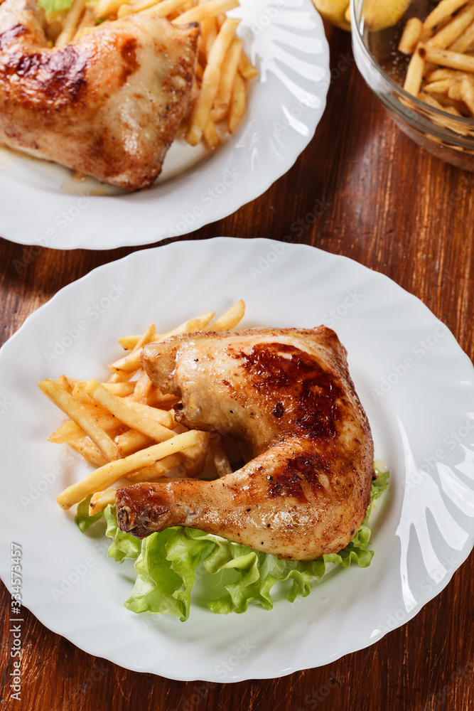 Roasted chicken legs with french fries and lettuce