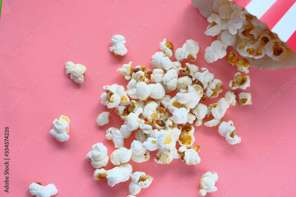 top view of popcorn spilling on pink background top view of popcorn spilling on pink background