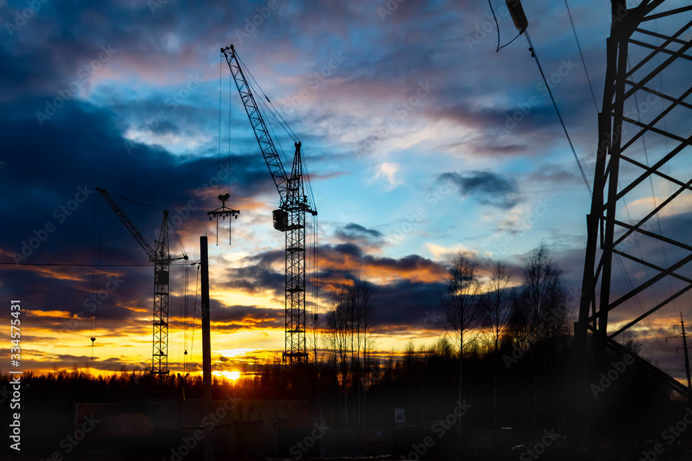 High cranes build the house in the evening. Sunset. Russia. Background.
