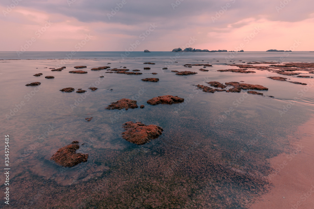 Fototapeta premium Beautiful sunset seascape. Coral reef at Hikkaduwa, Sri-Lanka. Textured ocean coast with waves on long exposure.