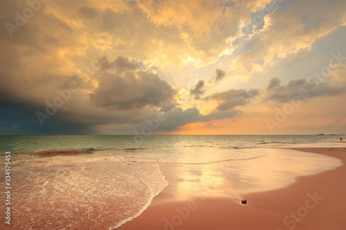 Foamy waves on sandy ocean beach under a beautiful sunset sky with clouds on Sri Lanka island.
