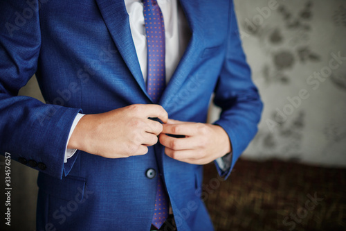 the groom straightens the wedding suit