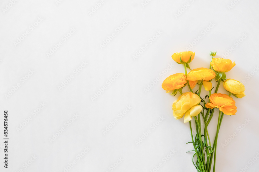 Beautiful bouquet of yellow ranunculus flowers with visible petal texture structure. Close up composition with bright patterns of flower buds with a lot of copy space for text. Top view.