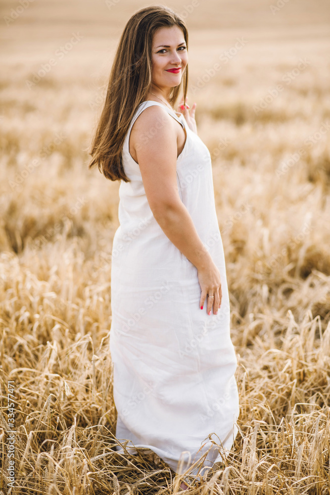 beautiful girl with brunette hair on a wheat field background. warm summer time. 