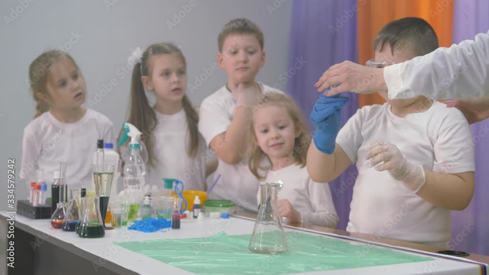 Chemical experiments for children. A woman adds ingredients to a flask for chemical experiments. A column of smoke rises from the beaker . Bright emotions of children and adults, surprise, admiration Chemical experiments for children. A woman adds ingredients to a flask for chemical experiments. A column of smoke rises from the beaker . Bright emotions of children and adults, surprise, admiration