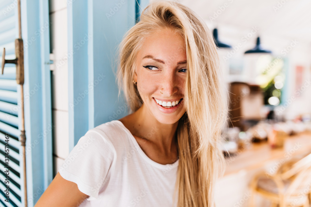 Close-up portrait of laughing blonde woman wears white t-shirt. Outdoor shot of caucasian girl with straight hair looking away with smile. Close-up portrait of laughing blonde woman wears white t-shirt. Outdoor shot of caucasian girl with straight hair looking away with smile.