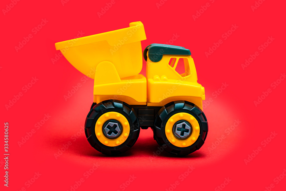 Yellow Toy Car Truck Over Red Background, studio shot, industrial cargo Yellow Toy Car Truck Over Red Background, studio shot, industrial cargo
