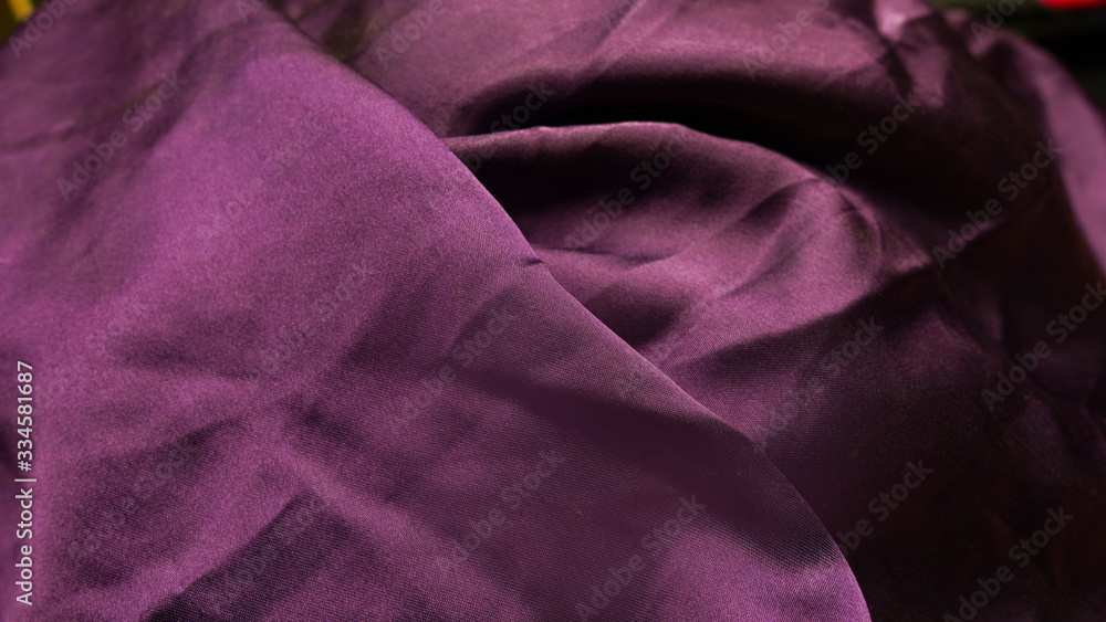 Obraz premium Abstraction, background of silk purple matte fabric. Dark drapery fabric. Satin texture. Beautiful fashionable silk color of fabric.