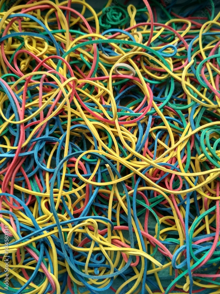 Elastic bands are multicolored. Top view. Textured image. Yellow, red, blue elastic bands in one pile