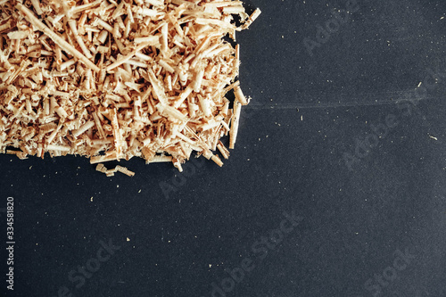 Wood shavings on black background. Background of fresh wood shavings. Copy, empty space for text