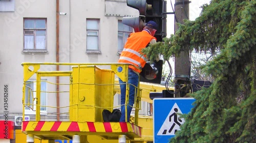 Electrical workers are busy repairing a broken traffic light on a busy intersection. Traffic light repairman worker