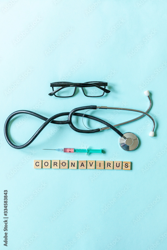 Text phrase Coronavirus syringe eyeglasses and stethoscope on blue pastel background. Novel coronavirus 2019-nCoV MERS-Cov covid-19 middle East respiratory syndrome coronavirus virus vaccine concept. Text phrase Coronavirus syringe eyeglasses and stethoscope on blue pastel background. Novel coronavirus 2019-nCoV MERS-Cov covid-19 middle East respiratory syndrome coronavirus virus vaccine concept.
