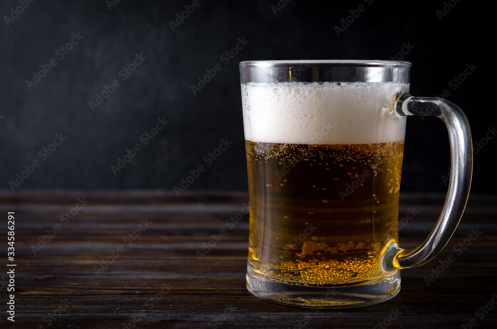 alcoholic beverage , mug of light beer with foam on a dark wooden background,
