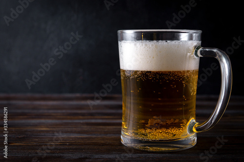 alcoholic beverage   mug of light beer with foam on a dark wooden background 