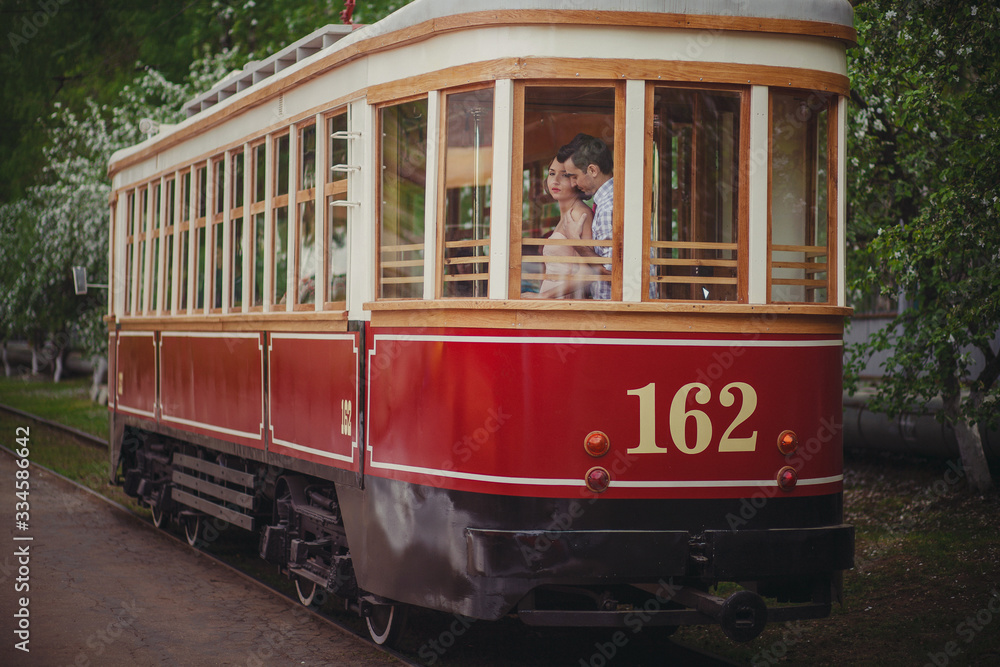 A guy and a girl in retro clothes with vintage hairstyles are standing inside an old tram