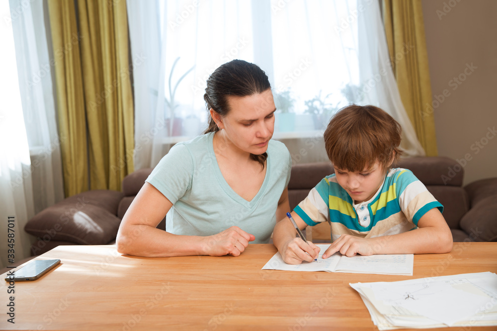 Mom helps child boy do lessons at home. kid study at home. quarantine. Corona Virus. Mom helps child boy do lessons at home. kid study at home. quarantine. Corona Virus.