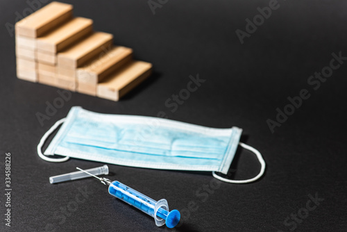 Schedule of reduction from wooden blocks, pandemic, disease. Syringe, medical mask, blood tests. Financial concept. Copy the space. on a dark background  photo