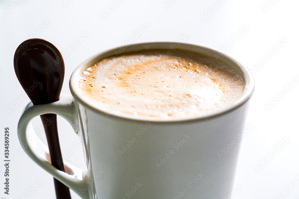 Creamy latte in a white cup with a spoon. Creamy latte in a white cup with a spoon.