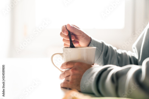 Tableau sur toile Person stirring a coffee cup with a ceramic spoon