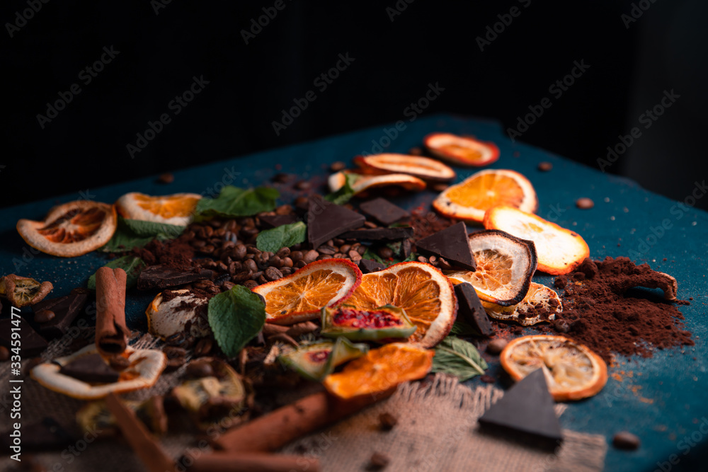 dark decorated table with coffee beans, dry oranges,dry lemons,dry Sabras fruit,dry kiwi,dark chacolate,cinnamon sticks..place for the text.
