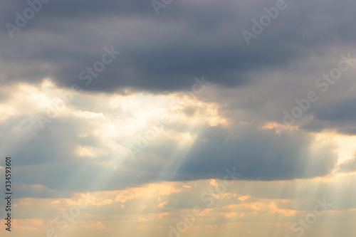 Sky background with rays through the clouds at sunset