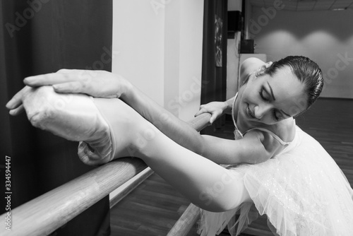 Fotobehang Ballerina stretching on handrail in ballroom