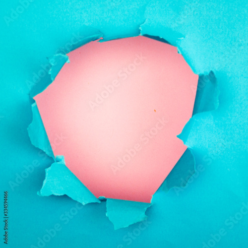 torn sheet of paper, hole in torn paper, blue torn sheet on a pink background, place for text