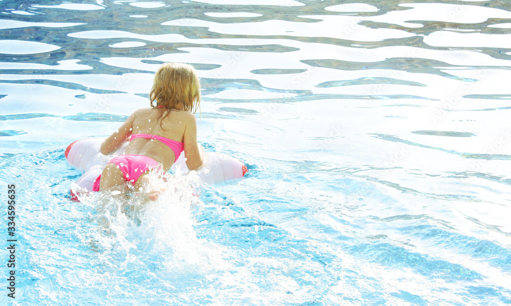 Children blond girl enjoying summer vacations at the swimming pool