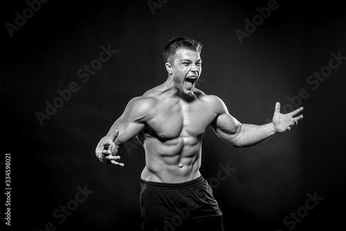 Sexy young athlete posing on a black background in the Studio. Fitness, bodybuilding, black and white © Andrii