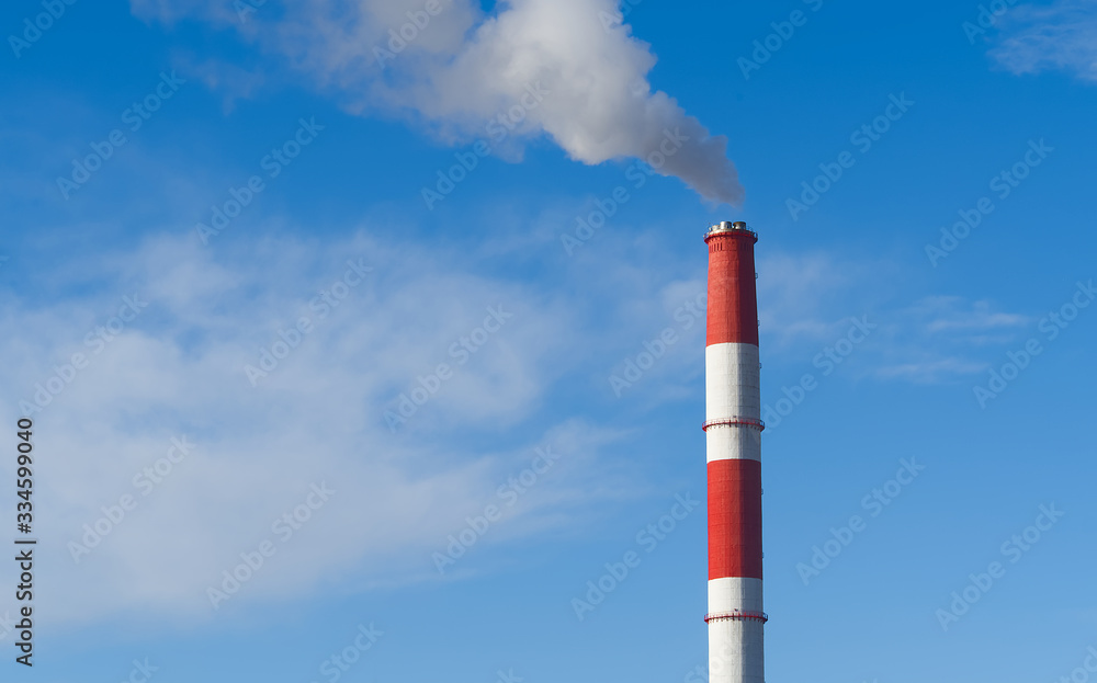 red and white smoking chimneys of the factory on blue sky. red and white smoking chimneys of the factory on blue sky.