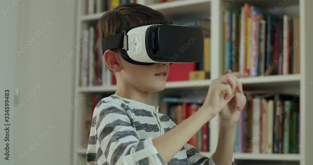Boy wearing virtual reality headset playing game. Head and shoulders of boy playing game using VR technology. Real-time, hand-held shot, medium shot, 4K. Boy wearing virtual reality headset playing game. Head and shoulders of boy playing game using VR technology. Real-time, hand-held shot, medium shot, 4K.