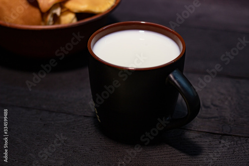 Milk with pancakes on oak table