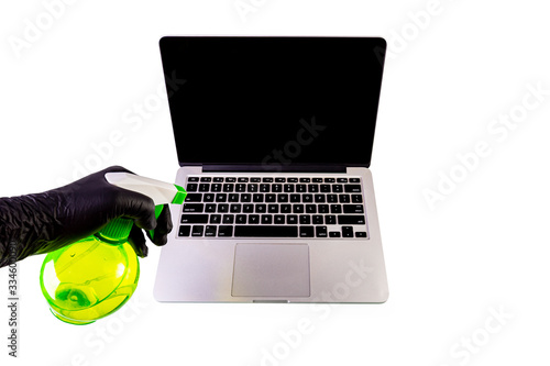 Hand cleaning a laptop with a spray bottle sanitizer photo