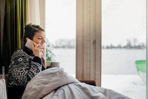 Canvas Print Young woman talking on the mobile phone from bed