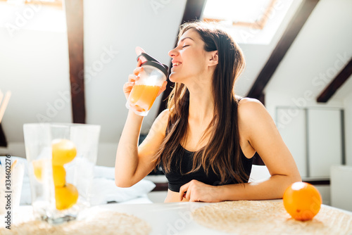 Woman at home drinking orange flavored amino acid vitamin powder.Keto supplement.After exercise liquid meal.Weight loss fitness nutrition diet.Immune system support.Organic citrus fruit.Strong body photo
