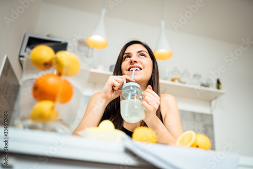 Healthy cheerful woman drinking homemade organic mixed citrus fruit drink.Making lemonade.Detox diet,nutrition.Food for oily skin,strong immune system,fitness meal.Natural antioxidants vitamins source